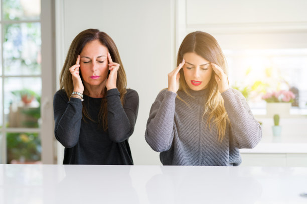 美丽家庭的母女一起在家里用手顶着头因为压力而痛苦。遭受偏头痛。图片下载