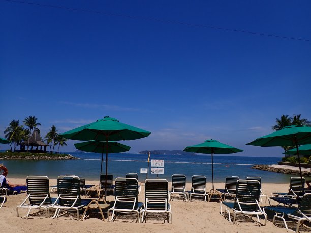 阳光明媚的一天，坐在沙滩上的躺椅上放松。图片下载