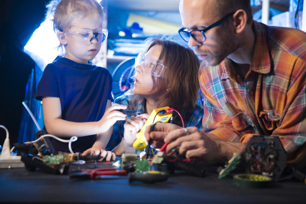 女人测试电路板，男孩和男人看着她图片下载