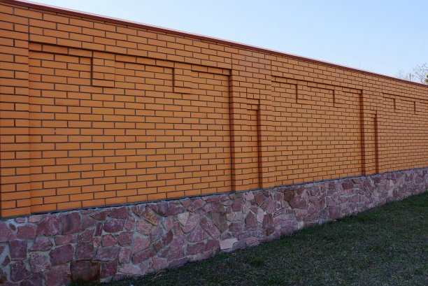 长长的棕色的砖和石头篱笆在绿色的草地上图片下载