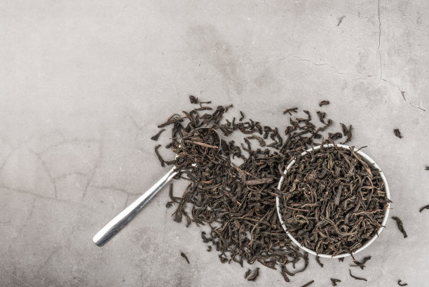 干茶在一个白色陶瓷杯和勺子在灰色纹理的背景。从以上观点。布局。图片下载