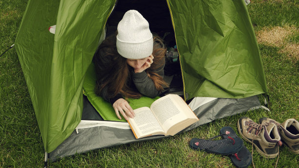 露营活动。一个在帐篷里看书的女人图片下载