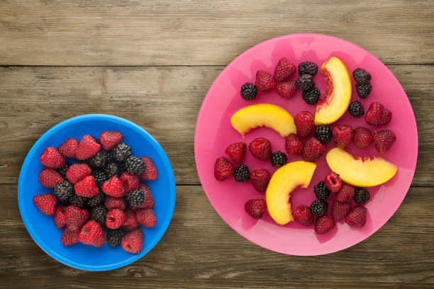 饮食,健康食品。黑莓、覆盆子、油桃一盘盘上。木制背景上的素食图片下载
