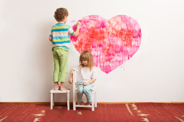 两个孩子在墙上画心形。快乐家庭日概念素材图片