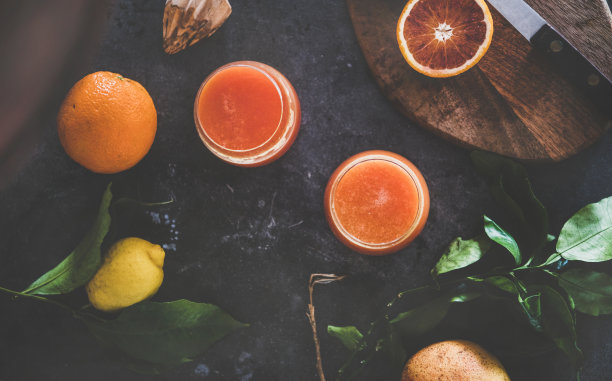平铺在玻璃杯中的橙汁和新鲜柑橘类水果图片下载
