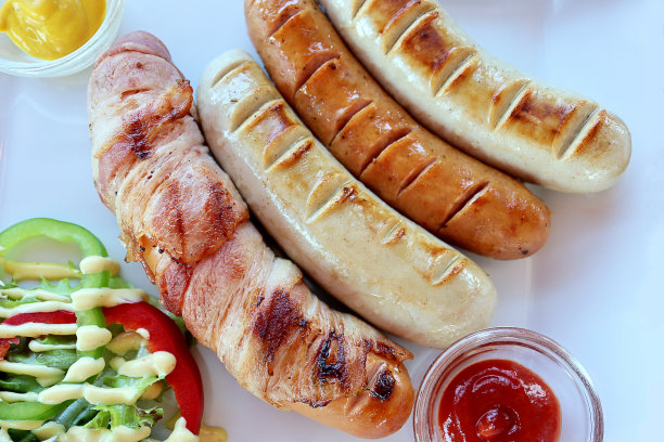 俯视图德国猪肉香肠和沙拉蔬菜与酱汁在白色盘子的背景。食品的概念。图片下载