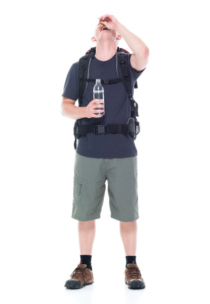 迷人的年轻男性徒步旅行者吃和喝零食图片下载