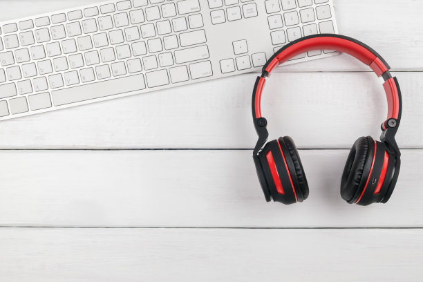 顶视图的红色耳机和白色键盘上的白色木制桌子图片下载