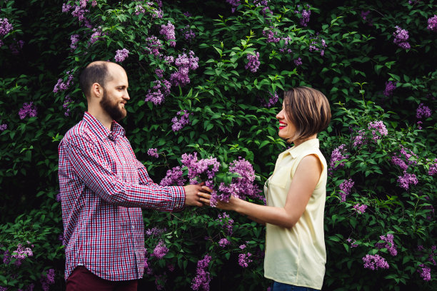 一个长着胡子的年轻男子送给一个女孩一束丁香花。图片下载