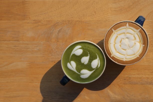 两杯不同的咖啡，绿茶抹茶拿铁和焦糖拿铁牛奶在晨光和阴影和拷贝空间的乡村木制桌子上图片下载