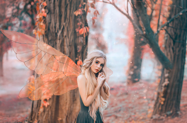 阳光明媚的夏日照片，神秘的森林仙女爱上了王子，木偶脸的女孩，金色的长发和蓝色的眼睛，穿着绿色衣服的女士谦虚地窥视，饶有兴趣图片下载