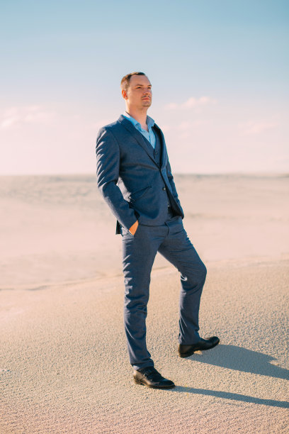 穿着蓝色时尚西装的商务男士在沙漠中沉思图片下载