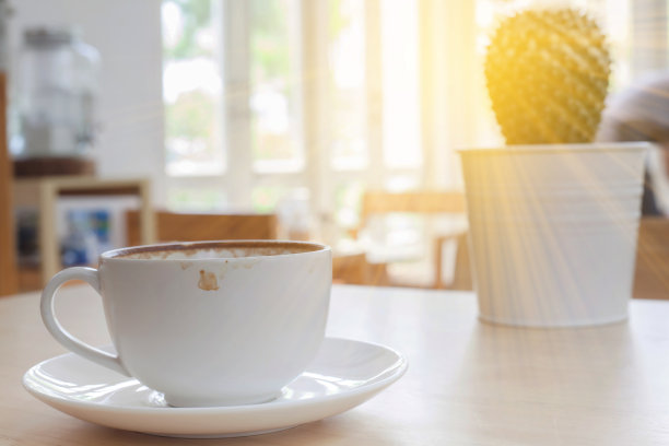 一杯热拿铁咖啡，放在木桌上，有透光的窗户。图片下载