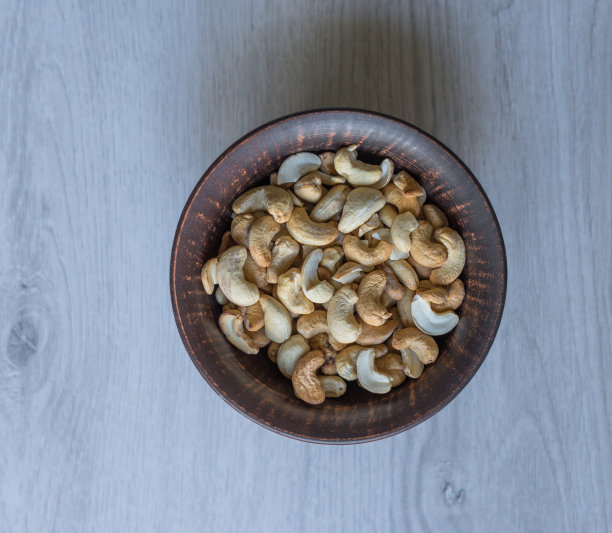 健康的食物背景图片特写腰果。坚果纹理在白色灰色的桌子上的杯子盘上的视图图片下载