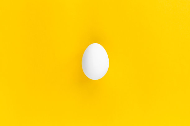 一个白色鸡蛋的中心是黄色的背景。健康有机食品与饮食理念。复活节主题图片下载