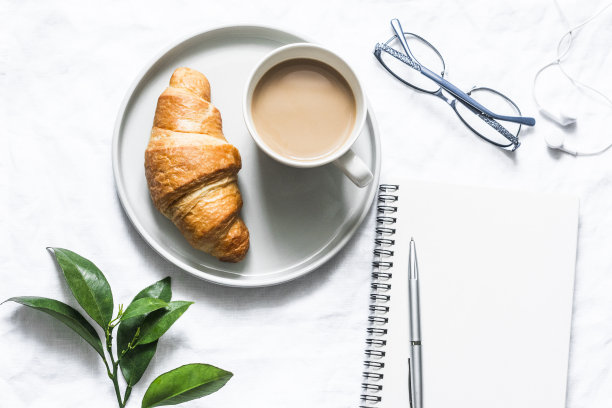 早上的计划。咖啡，牛角面包和一个干净的空笔记本在一个明亮的背景，俯视图。平铺，拷贝空间图片下载