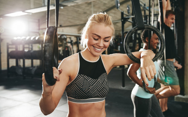 笑嘻嘻的年轻女子在健身房用吊环健身图片下载