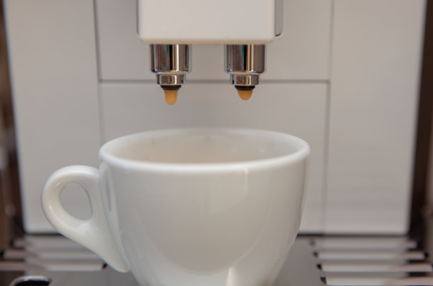 咖啡机将咖啡豆制成一个白色的杯子。新鲜研磨的咖啡香气与美味图片下载