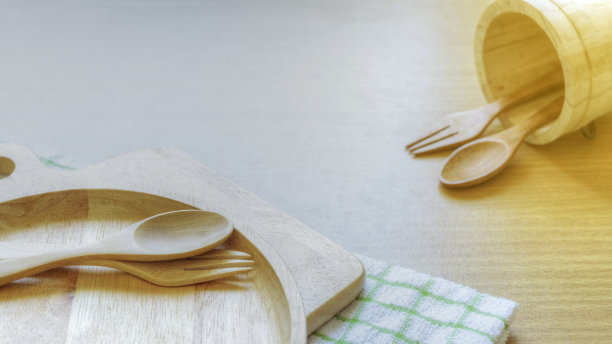 俯视图特写一套木制餐具器具。木制的叉子，勺子，盘子在木制桌子的背景。干净的绿白格子手巾互相靠近。厨房的概念。图片下载
