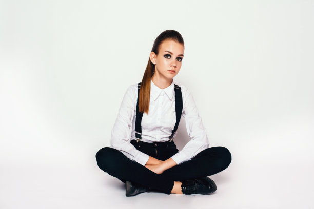 年轻漂亮的女孩，穿着白衬衫和黑色带背带的牛仔裤图片下载