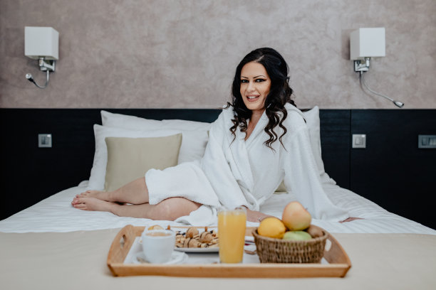 一个女人在旅馆房间的床上吃早餐图片下载