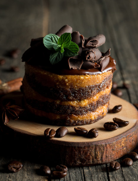 巧克力蛋糕在黑色木板薄荷，咖啡豆在黑暗的背景，特写照片。新鲜、美味的甜品理念。图片下载