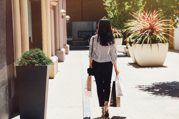 在阳光明媚的日子里，一个女孩在户外拿着购物袋图片下载