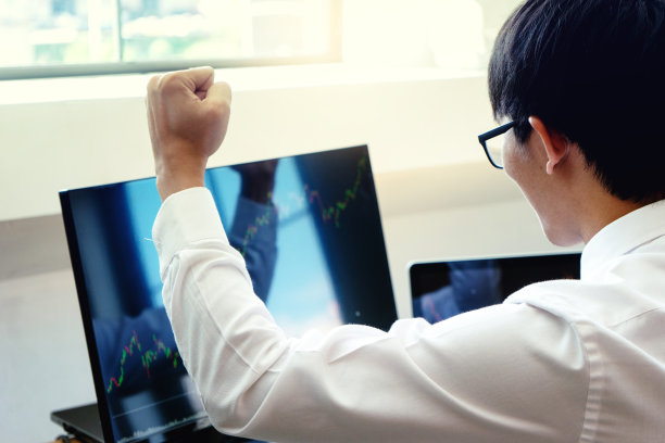 年轻的商人坐着看电脑看股票市场。图片下载