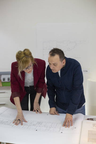 两位建筑师在办公室的办公桌上查看一个项目。有思想的设计师戴着眼镜思考和讨论项目。图片下载