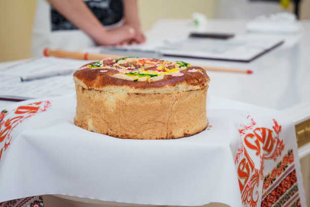 传统的婚礼面包在桌子上，旁边是一束花，一个枕头上的戒指和一个婚礼碗。水平的照片图片下载