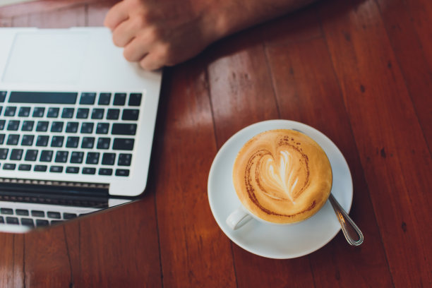 一个男人在大街上的咖啡店平台上用笔记本电脑打字的特写。图片下载