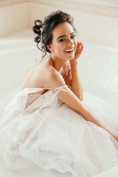 时尚照片美丽的新娘与黑色的头发在豪华的婚纱摆姿势在卧室图片下载