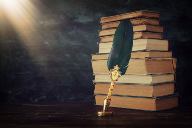 旧羽毛笔墨水瓶和旧书在木桌上，黑色的墙壁背景。老式和过滤的风格。关于历史、幻想、教育和文学主题的概念性照片图片下载