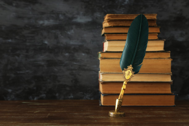 旧羽毛笔墨水瓶和旧书在木桌上，黑色的墙壁背景。老式和过滤的风格。关于历史、幻想、教育和文学主题的概念性照片图片下载