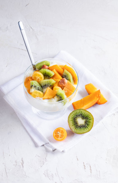 玻璃碗在茎上与酸奶，切片水果在白色的餐巾在白色的背景。图片下载