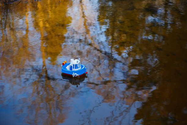 日落时，一条小玩具船在森林河上航行图片下载