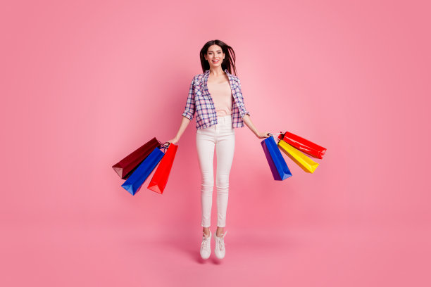 全身的身体尺寸照片美丽的她她女士跳高的手手臂购买惊人的商场黑色星期五穿鞋帽子休闲格子衬衫白色牛仔裤牛仔孤立的粉色背景图片下载