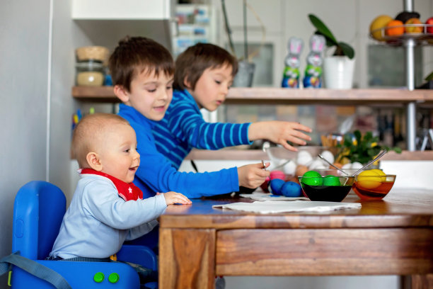 三个孩子，兄弟，在家里的厨房里涂画复活节彩蛋图片下载