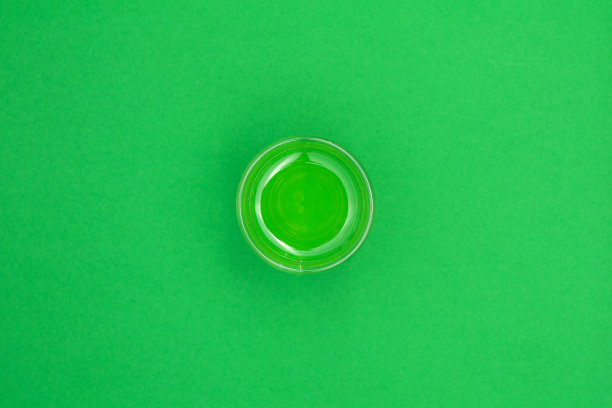 中间的背景是一杯绿色的水。前视图。图片下载