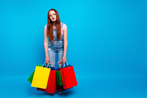 全身的身体尺寸照片美丽的她她的夫人买周末商店购物商场访问黑色星期五讨厌购物想家疲倦穿休闲牛仔裤牛仔工装裤衣服孤立的蓝色背景图片下载