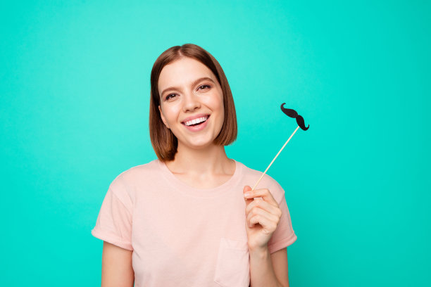 近距离的照片美丽有趣，时髦的她，她，女士短发，眨眼的眼睛，使胡子假装像男人，他，他，他的好穿休闲柔和的t恤，衣服孤立的蓝绿色背景图片下载