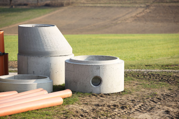 污水系统的混凝土结构元素在阳光的照射下躺在绿色的草地上。矿井的井壁为地下各种网络的布线提供了土井图片下载