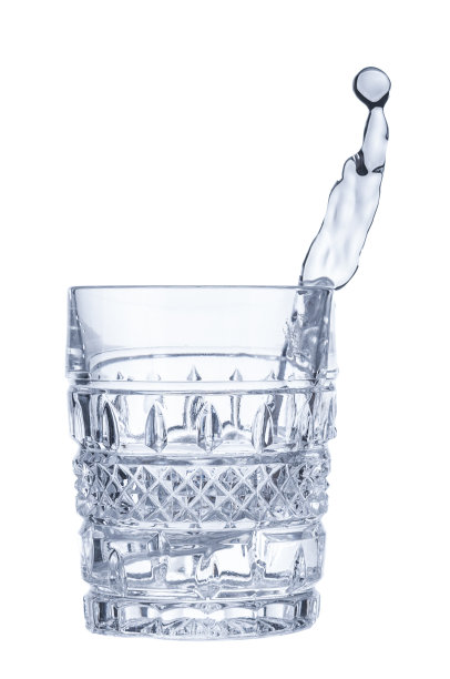 纯水从孤立在白色背景上的水晶玻璃中飞溅出来图片下载