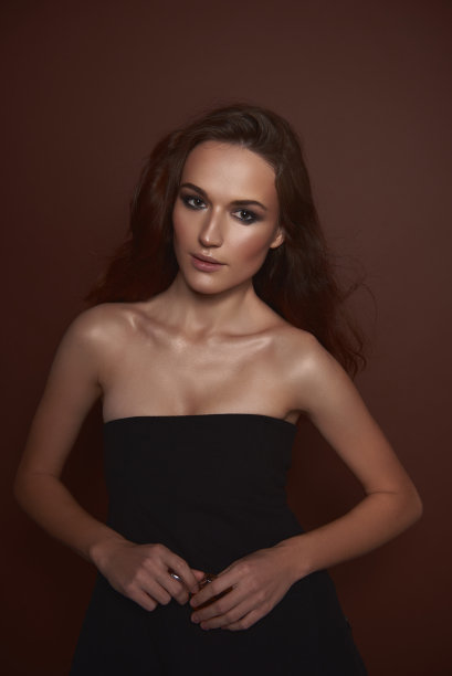 漂亮的年轻女子穿着优雅的黑色连衣裙，拿着香水图片下载