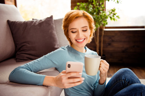 近距离的照片美丽的她她的女士读者的情书手电话智能手机热饮料穿蓝色套头衫牛仔裤牛仔衣服坐地板蓬松的地毯沙发房子阁楼客厅在室内图片下载