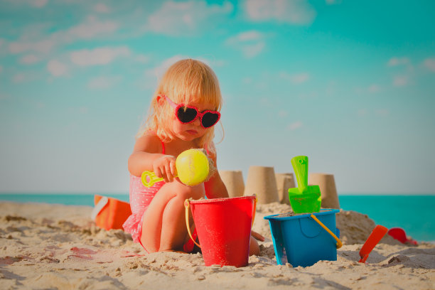 可爱的小女孩在海滩上玩沙子和玩具图片下载