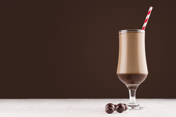 咖啡甜点在高脚杯与巧克力糖果和红色条纹稻草在深棕色的现代餐厅内部，复制空间。图片下载