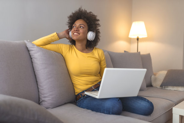 年轻女子戴着耳机在家听网络免费音频课程图片下载