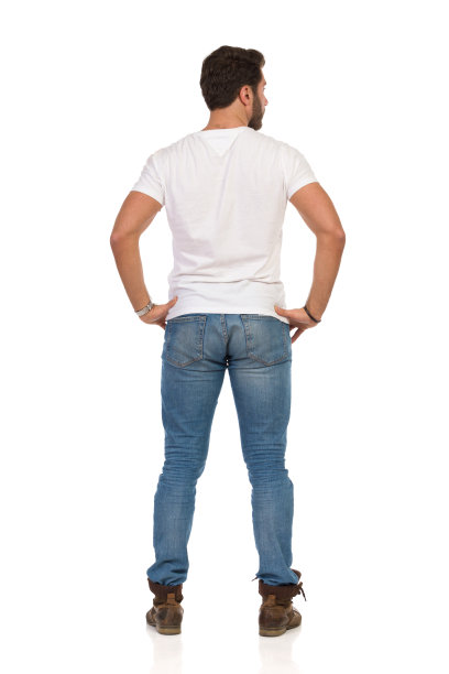后视图站立的男人在牛仔裤和白衬衫与手在臀部图片下载