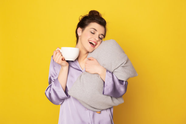 昏昏欲睡的女孩拥抱着孤立在黄色的枕头图片下载